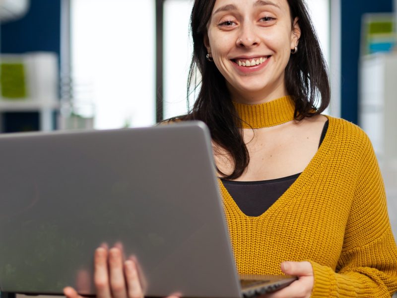 woman looking at camera smiling working in creative media agency